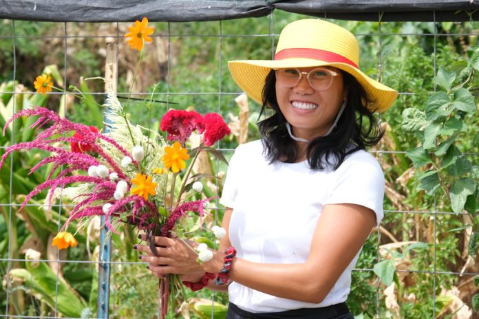 A woman holding a bouquet of flowers and standing in a garden.