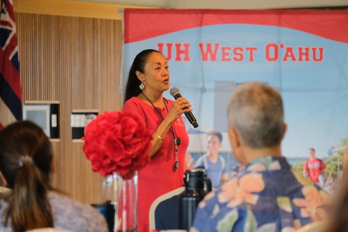 A woman holding a microphone and speaking in a room.