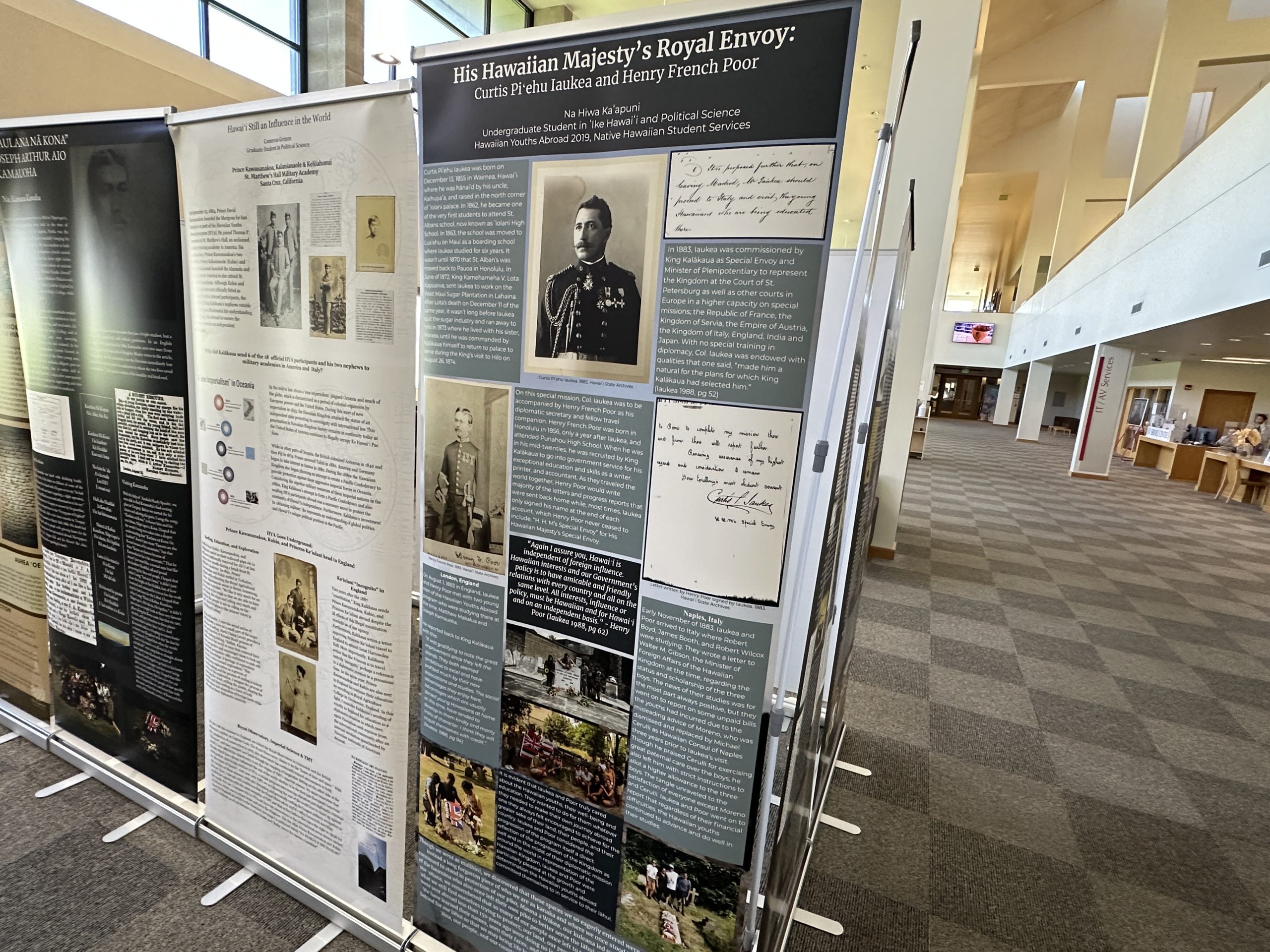 Closeup of posters with black-and-white and color photos, and writings, at a library exhibit.