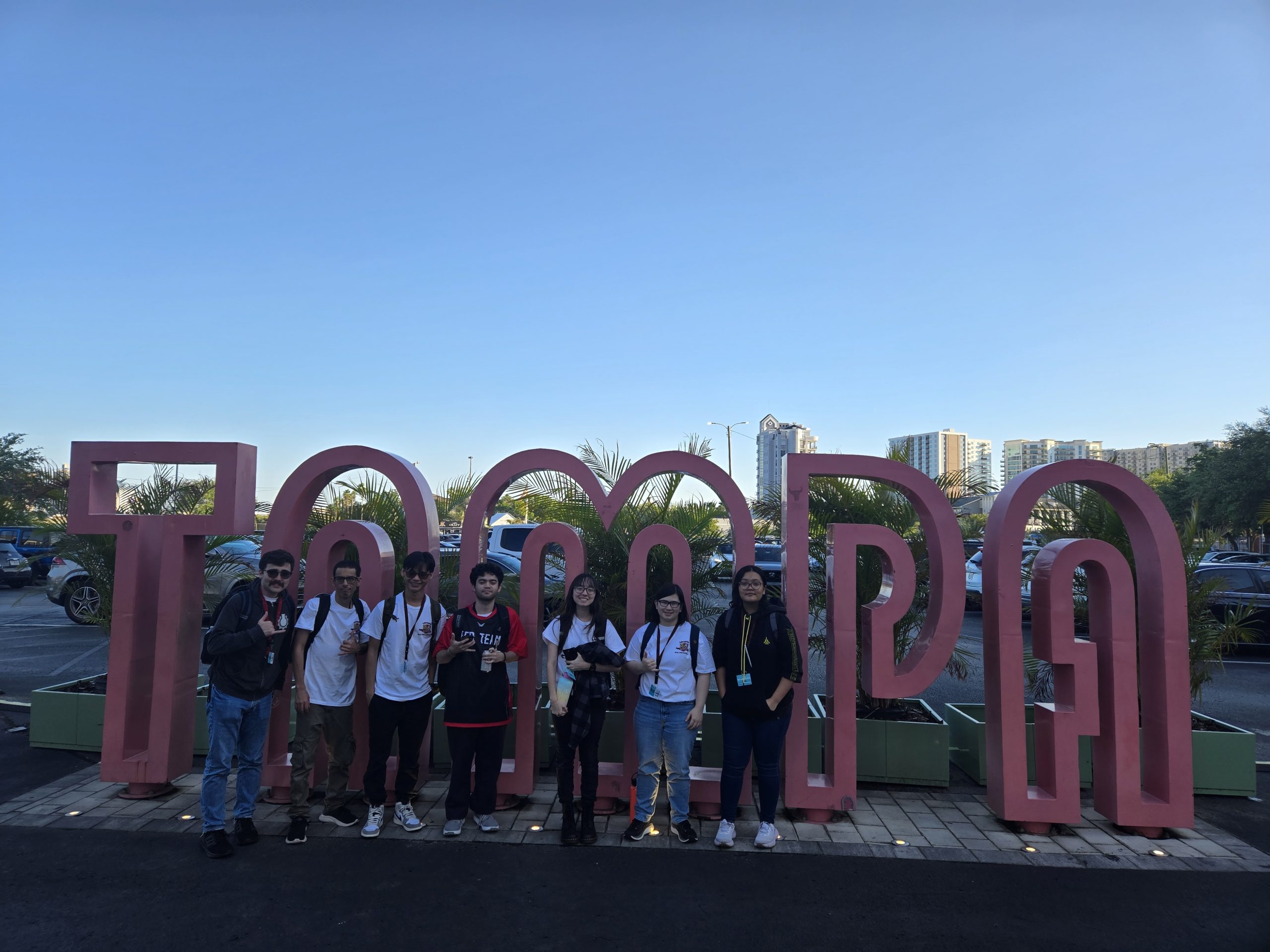 A group of students standing in front of a sculpture that says "TAMPA."