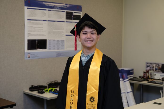 A man wearing a cap and gown, and standing in a room.