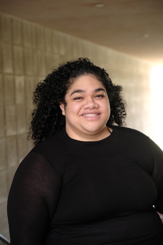 A woman smiling and standing in a breezeway.