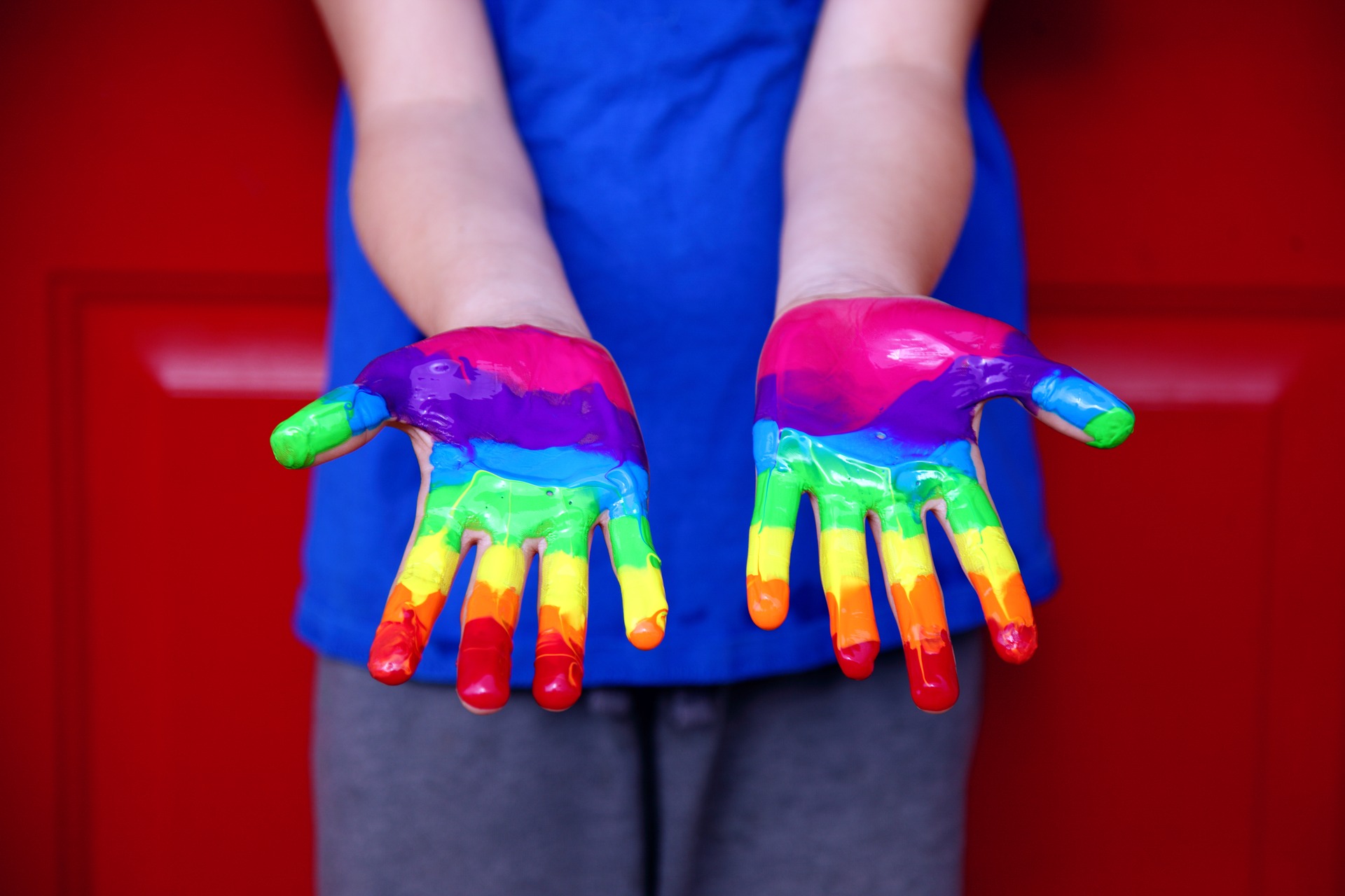 A picture of a pair of hands covered in paint, giving the effect of a rainbow.