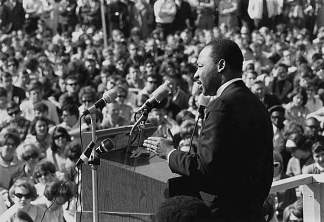 A picture of Martin Luther King giving a speech to a large crowd at St. Paul Campus