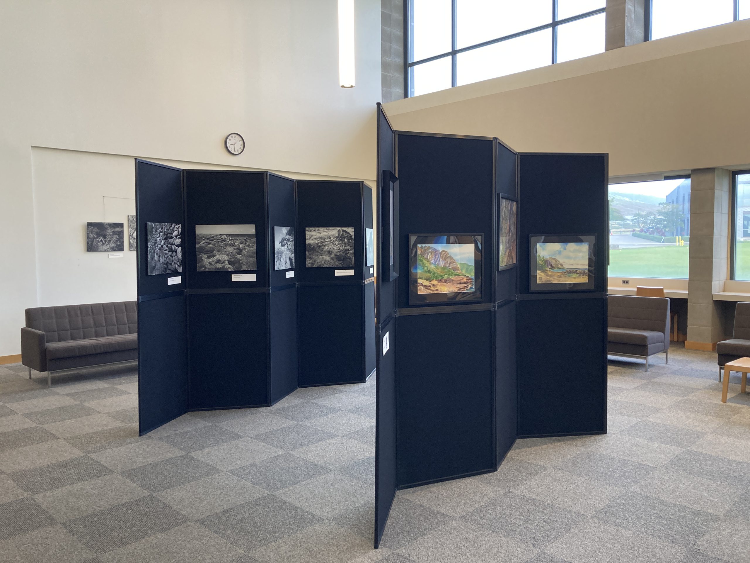 An image of two standing display panel walls that contain several framed pieces of artwork, related to the Kānehūnāmoku Exhibit.