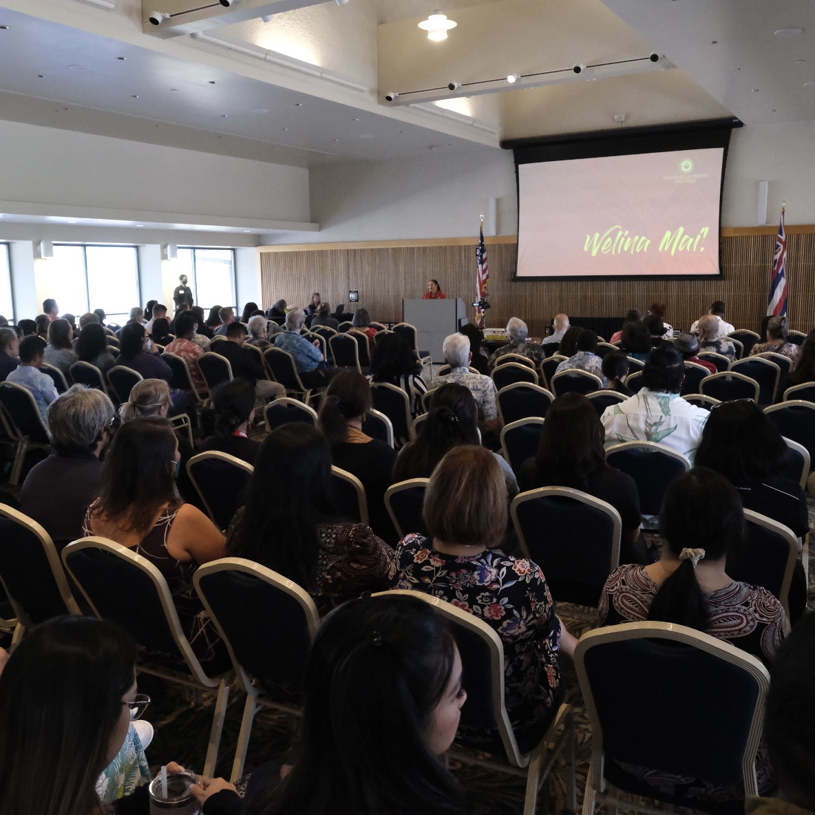 Image of an audience of hundreds seated in a room.
