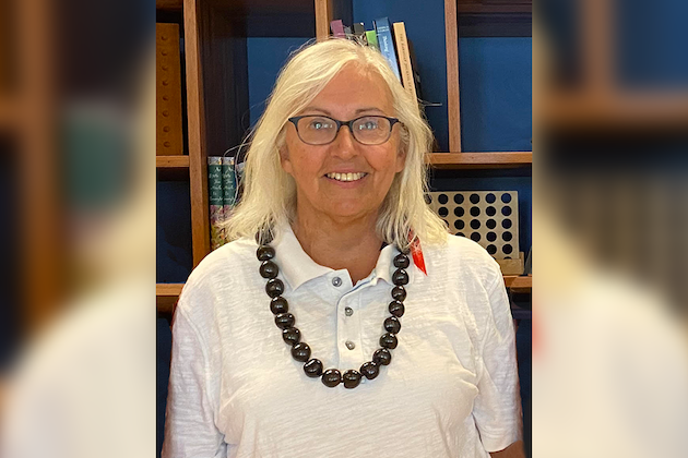 Adult female smiles wearing kukui lei.