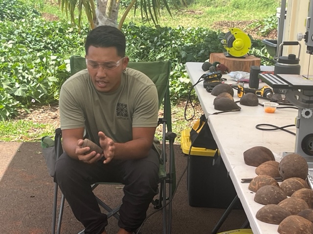 A man sitting holding a coconut shell while sitting on a chair outdoors.