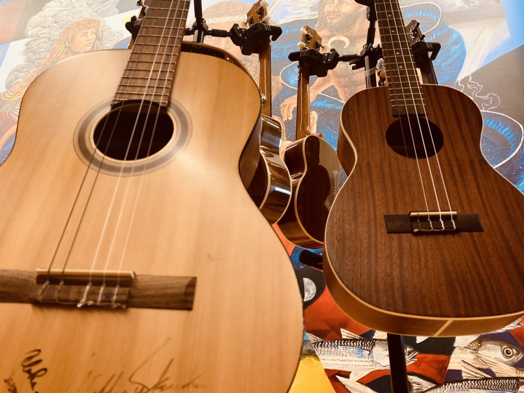 Image of a beige guitar and dark brown ukulele on stands located in the Naulu Center at UH West O'ahu