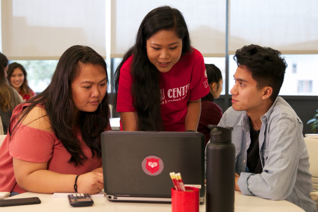 Tutor and two students working on a laptop