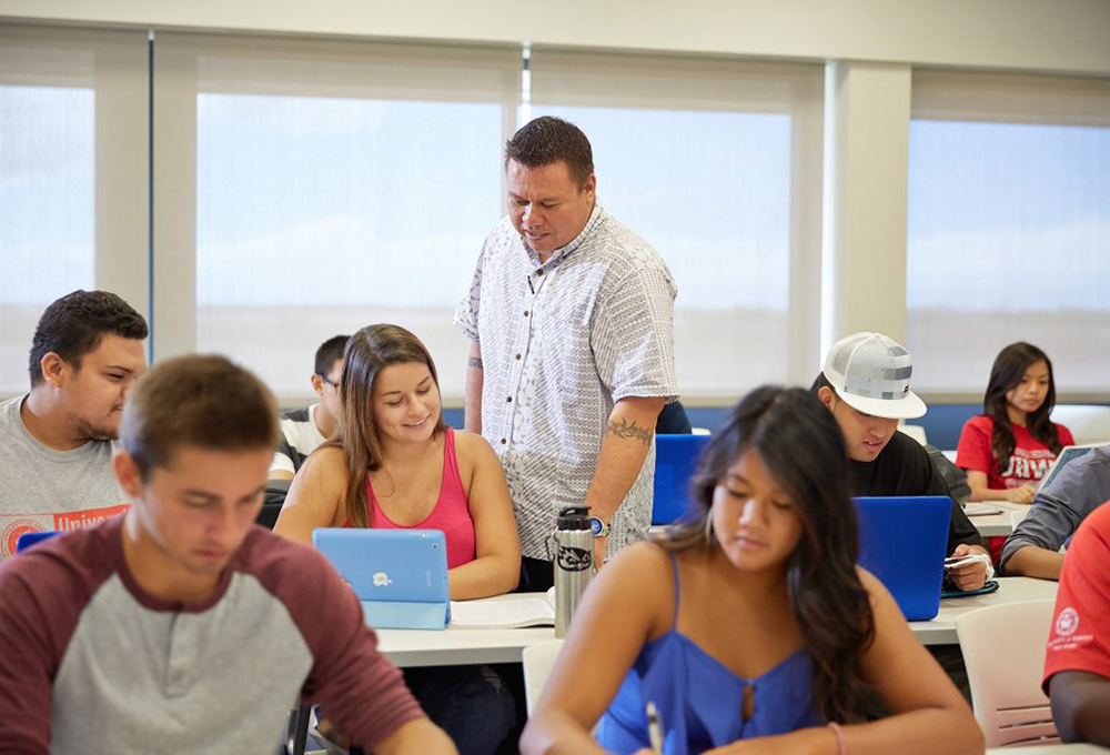 Professor assisting a student in a classroom.