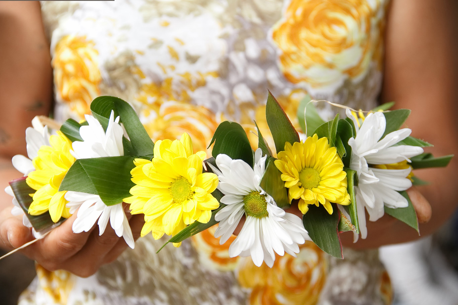 A close-up of someone holding a haku lei to the camera.