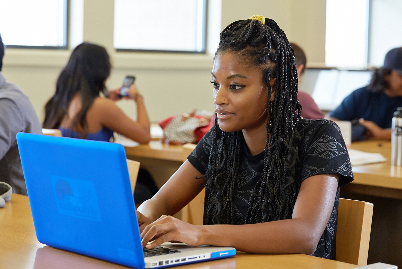 Student sitting in front of a blue laptop.