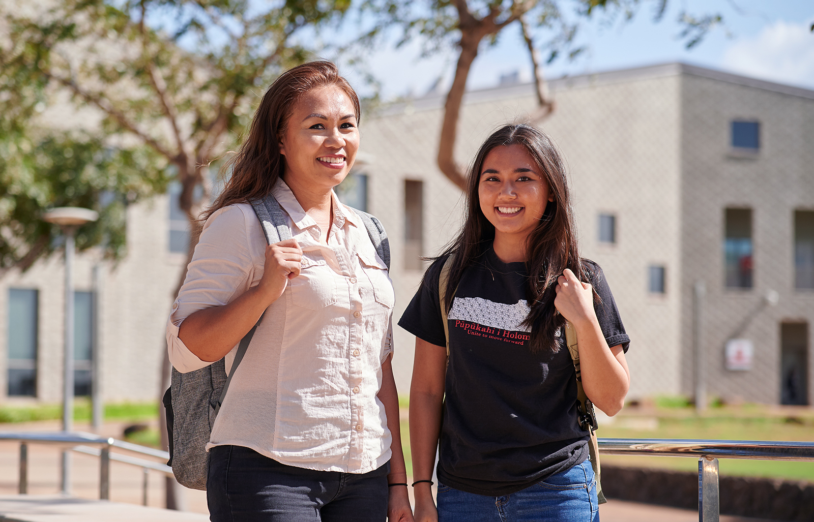 Two students standing and smiling in the campus mall area.