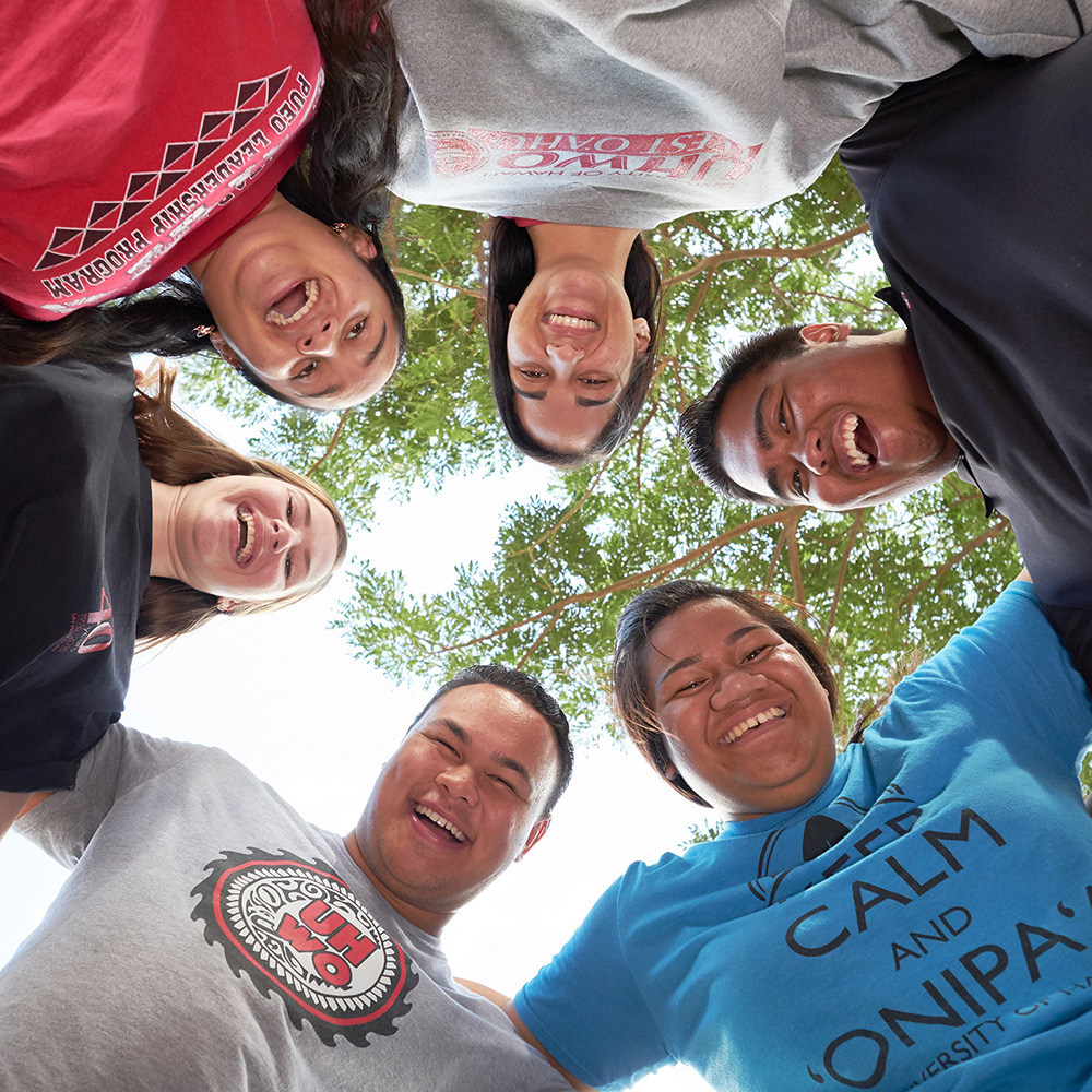 A group of 6 students looking downward toward the camera that is facing the sky.