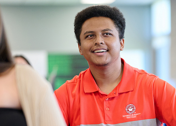Smiling Student Wearing A Red Polo Shirt In Class.