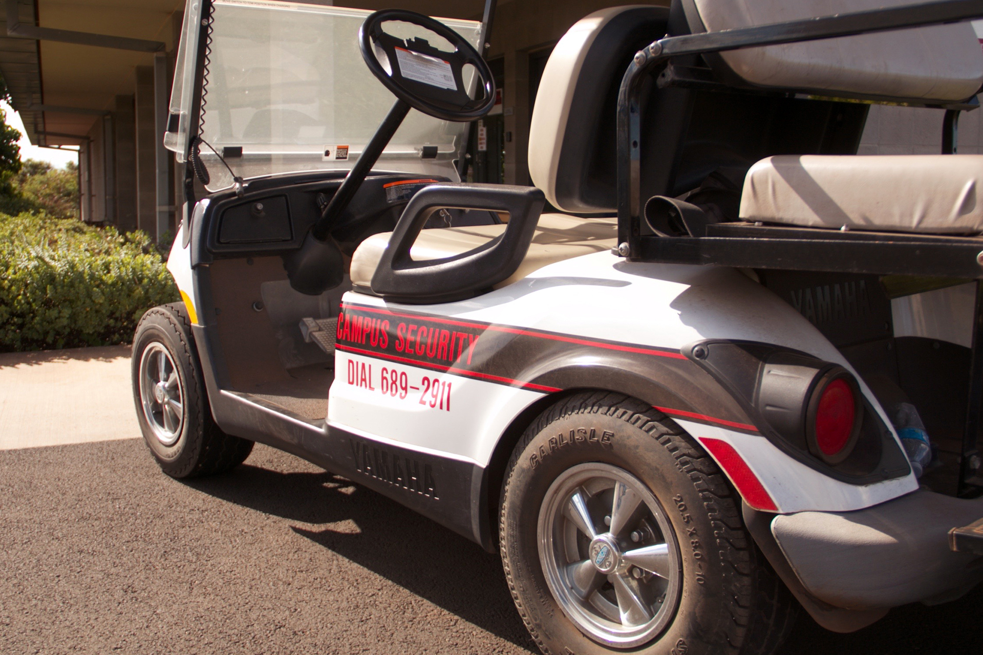 A close-up of a UH West Oahu security golf cart with the words Campus Security Dial 689-2911 displayed on the side.