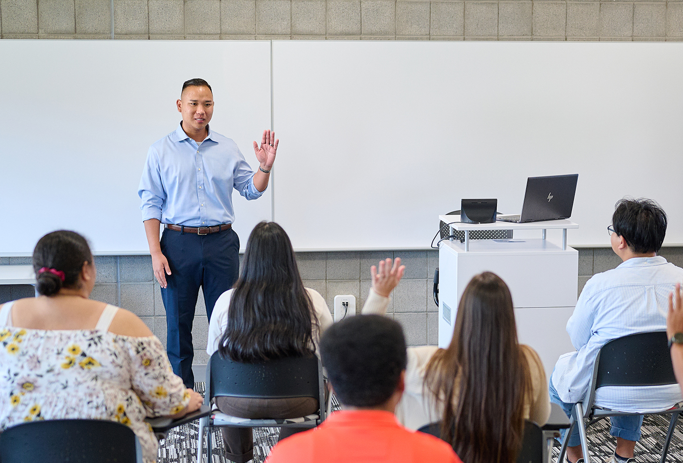 A faculty member addressing his class in a classroom.