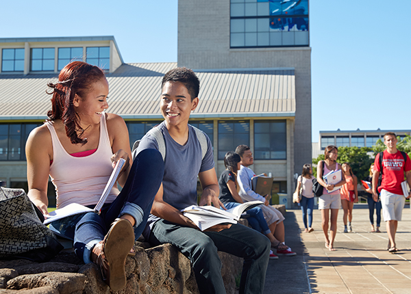 Students sitting on the wall fronting the campus library.