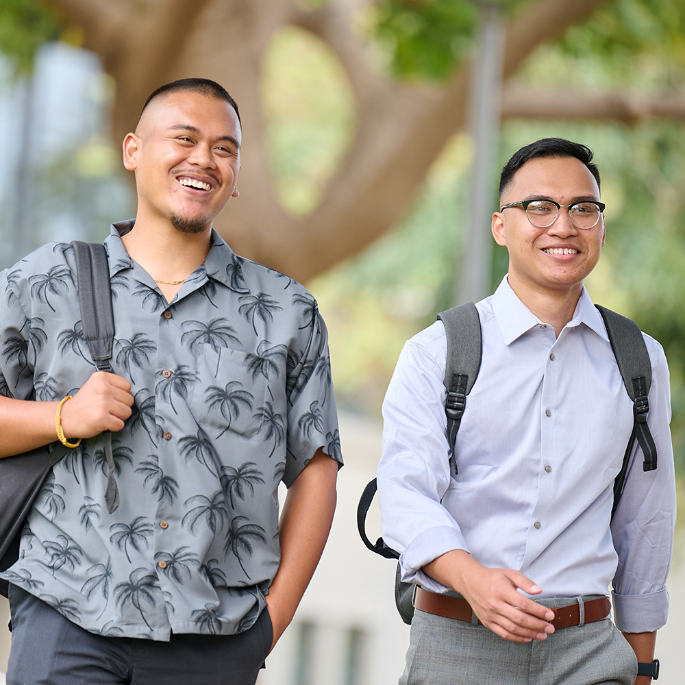 Two students smiling and walking in the courtyard.